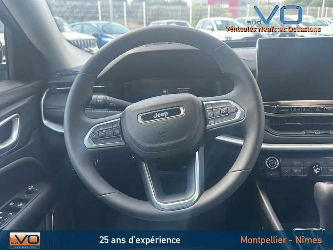 Vue intérieure centrée sur le volant Jeep du Compass 2024 avec tableau de bord et écran tactile visibles.