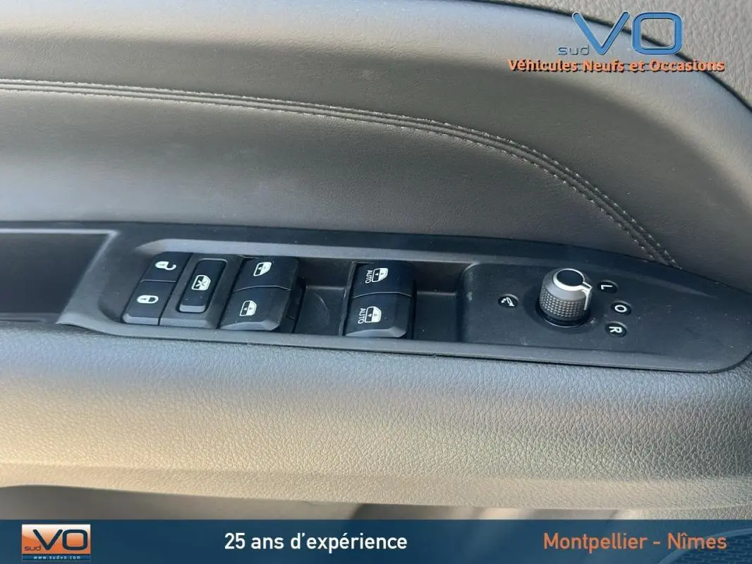 Vue intérieure sur la commande des vitres et rétroviseurs du côté gauche d'un Jeep Compass blanc 2024 avec pack hiver et roue de secours.