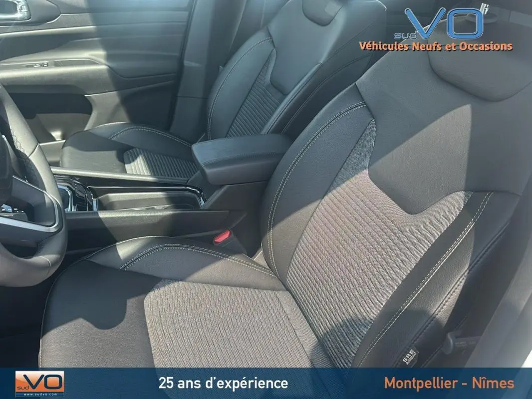 Vue intérieure rapprochée des sièges avant noirs du Jeep Compass 2024 avec coutures contrastées et accoudoir central.