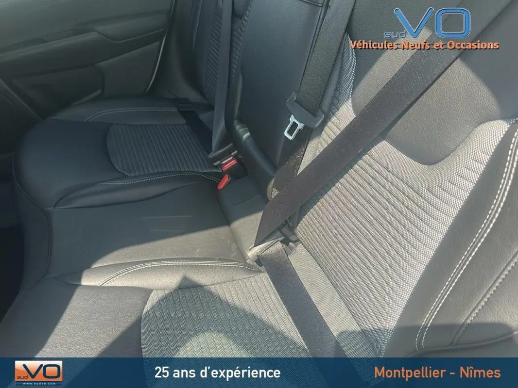 Gros plan sur les sièges arrière en cuir noir du Jeep Compass blanc 2024 avec ceinture de sécurité attachée.