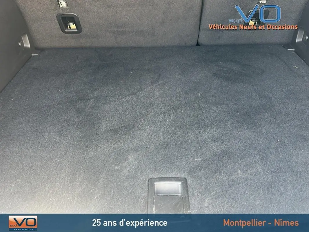 Coffre spacieux et vide du Jeep Compass blanc 2024, version e-Hybrid Altitude, avec tapis noir et poignée centrale.