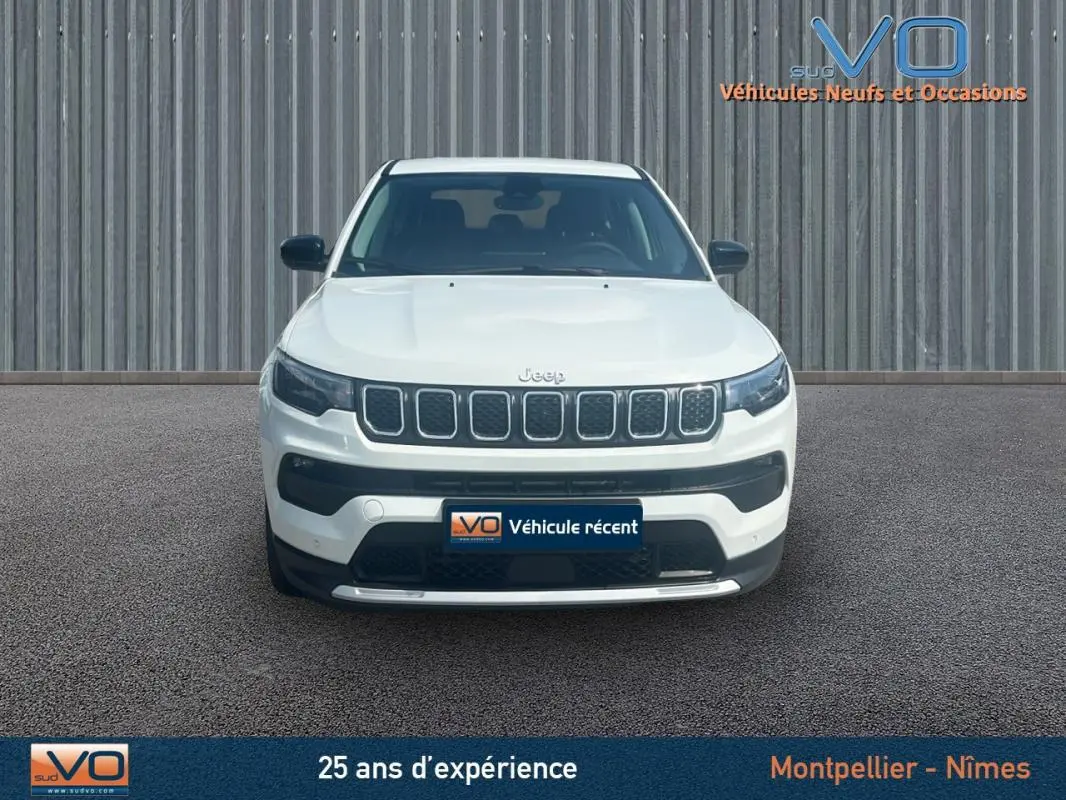 Vue frontale d'un Jeep Compass blanc 2024 avec calandre distinctive et plaques d'immatriculation du concessionnaire.