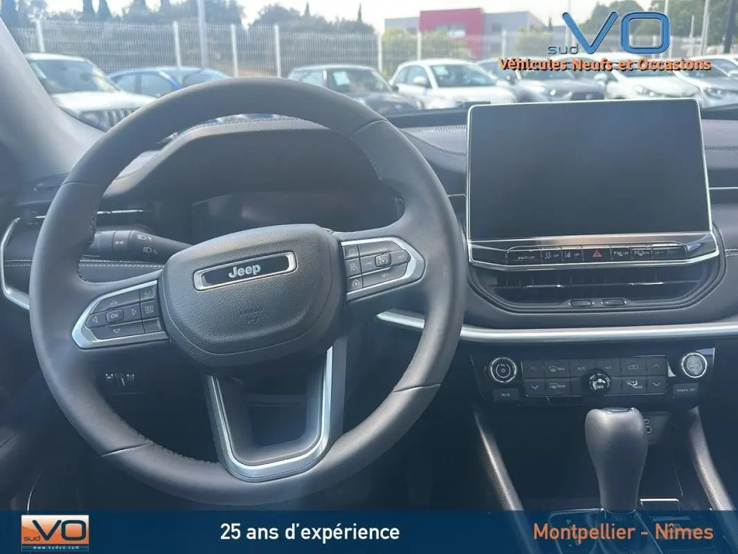 Vue intérieure centrée sur le volant Jeep et l'écran tactile du tableau de bord du Compass 2024.