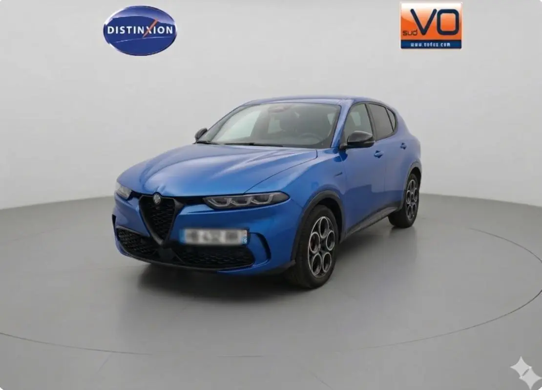 Vue 3/4 avant d'une Alfa Romeo Tonale 2025 bleu foncé avec calandre triangulaire et jantes distinctives à cinq cercles.