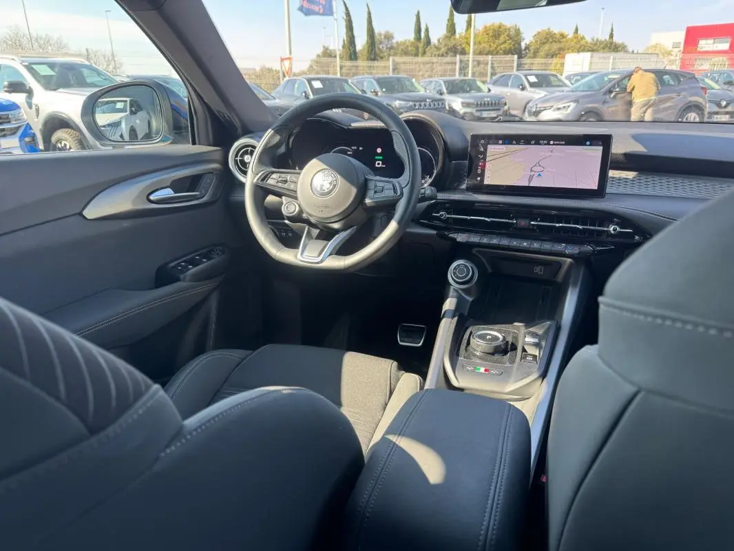 Vue intérieure avant de l'Alfa Romeo Tonale bleu foncé 2025, avec tableau de bord numérique et écran tactile central.