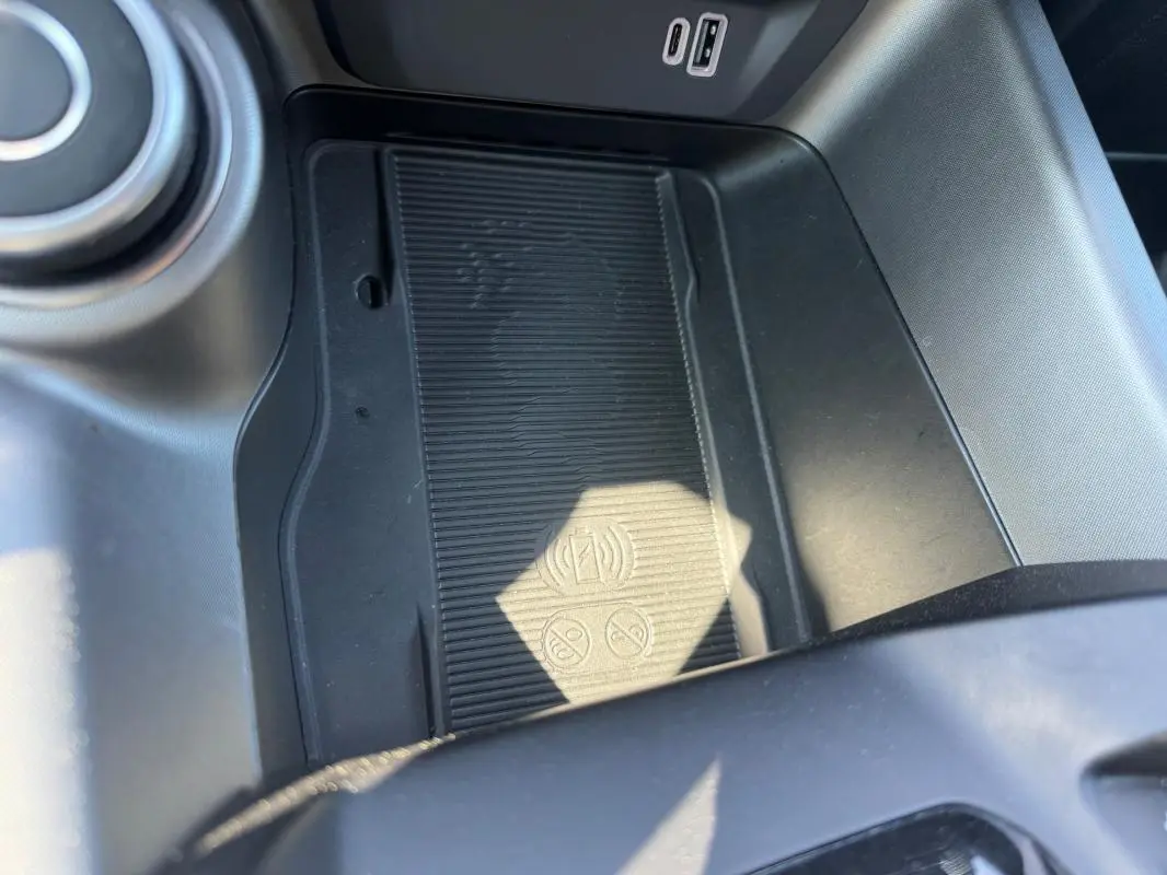 Détail de la console centrale de l'Alfa Romeo Tonale 2025 bleu foncé, montrant le chargeur sans fil et ports USB.