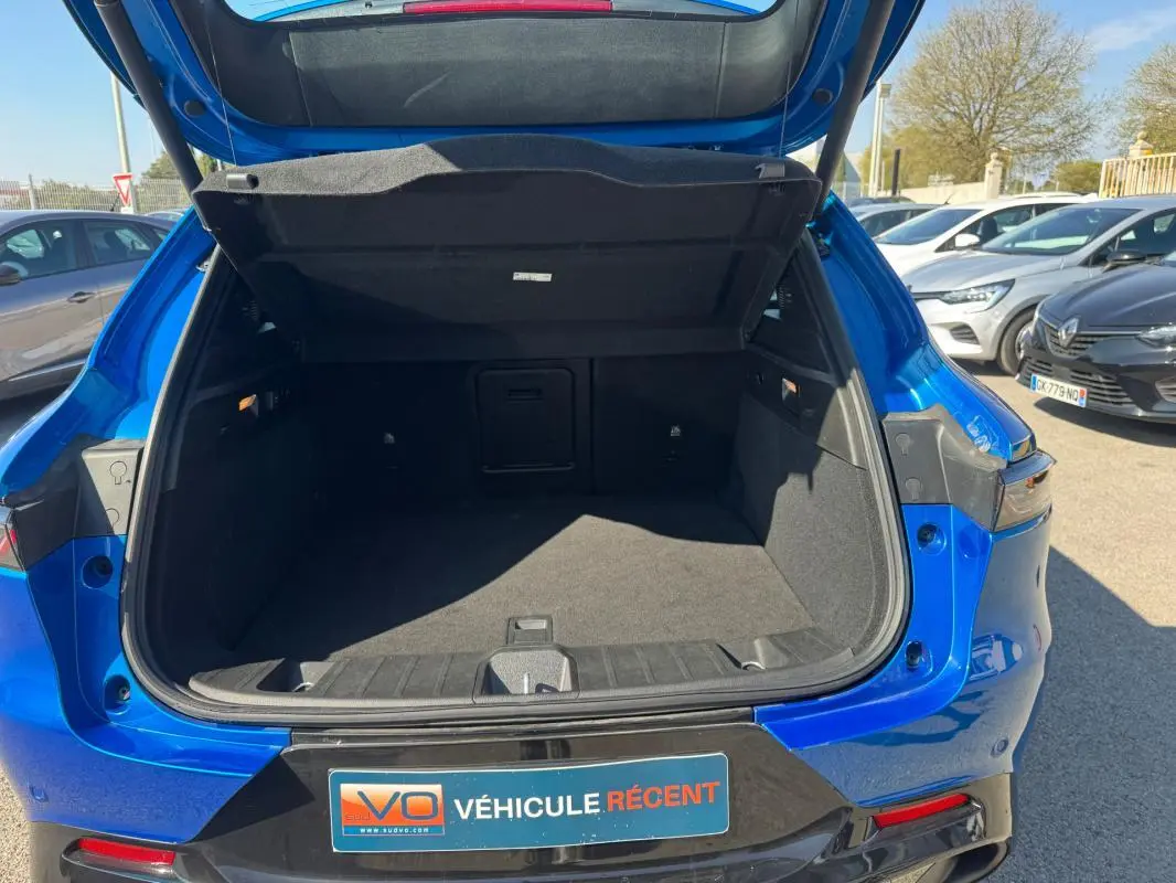 Coffre ouvert vu de l’arrière d’une Alfa Romeo Tonale bleu foncé, avec hayon relevé et intérieur spacieux visible.