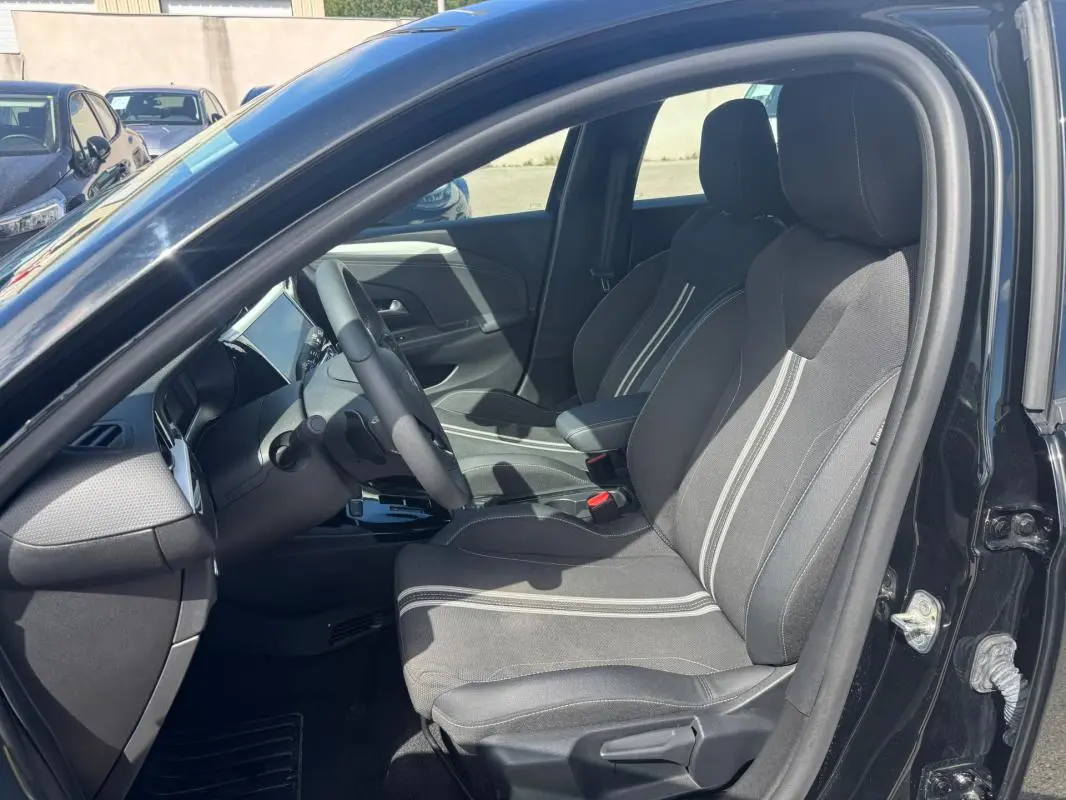 Vue intérieure côté gauche de l’Opel Corsa noire 2025, mettant en valeur les sièges avant avec surpiqûres claires.