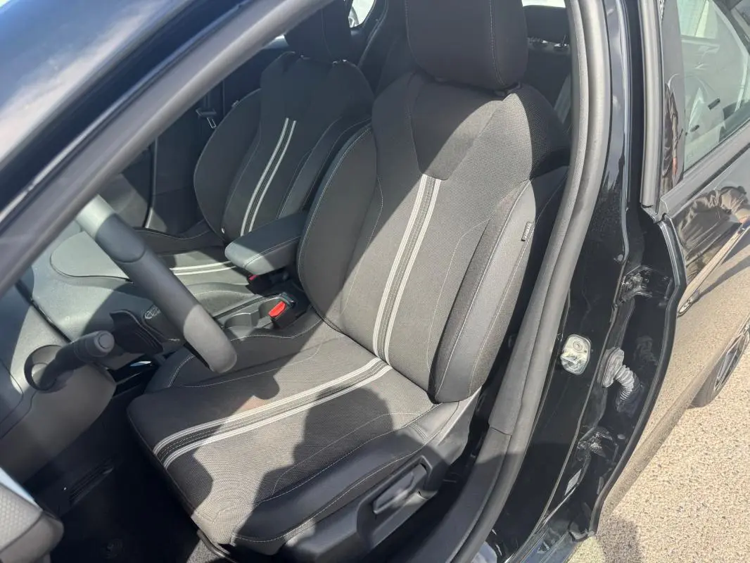 Vue intérieure côté conducteur de l’Opel Corsa noire 2025, mettant en valeur les sièges tissu avec bandes centrales claires.