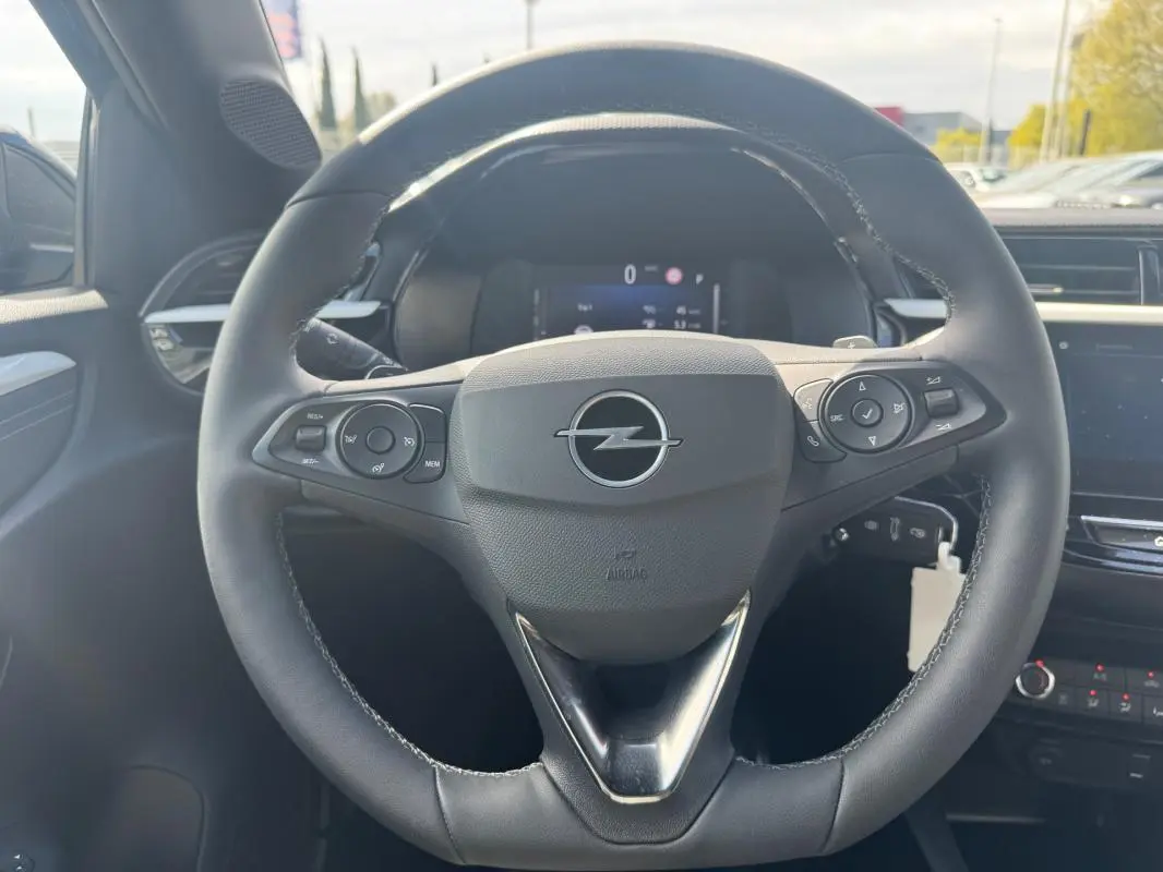 Vue rapprochée du volant noir de l’Opel Corsa 2025 avec commandes intégrées et logo central argenté.