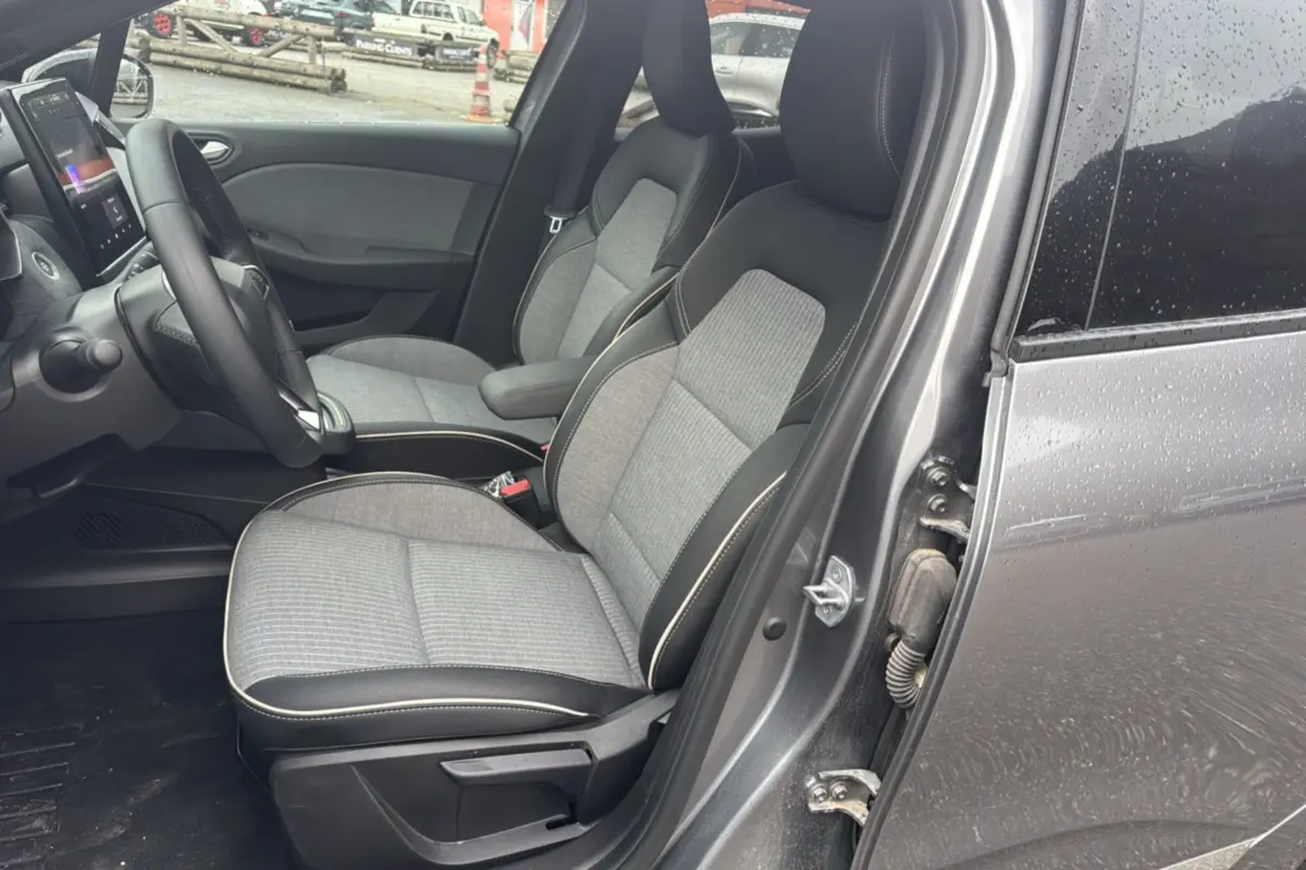 Vue intérieure côté conducteur de la Renault Clio gris schiste 2025, sièges tissu et cuir, tableau de bord avec écran tactile.