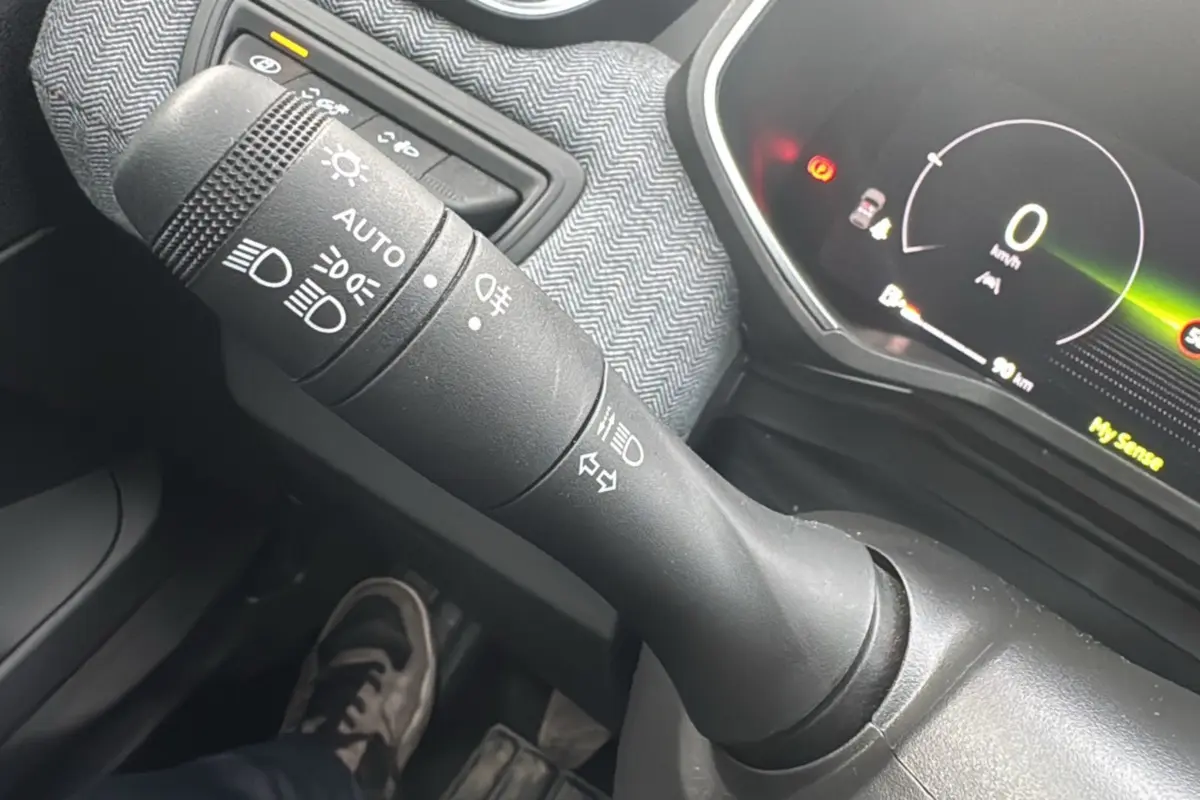 Gros plan sur la commande des feux et le tableau de bord numérique de la Renault Clio gris schiste V TCE 90 Techno Plus 2025.