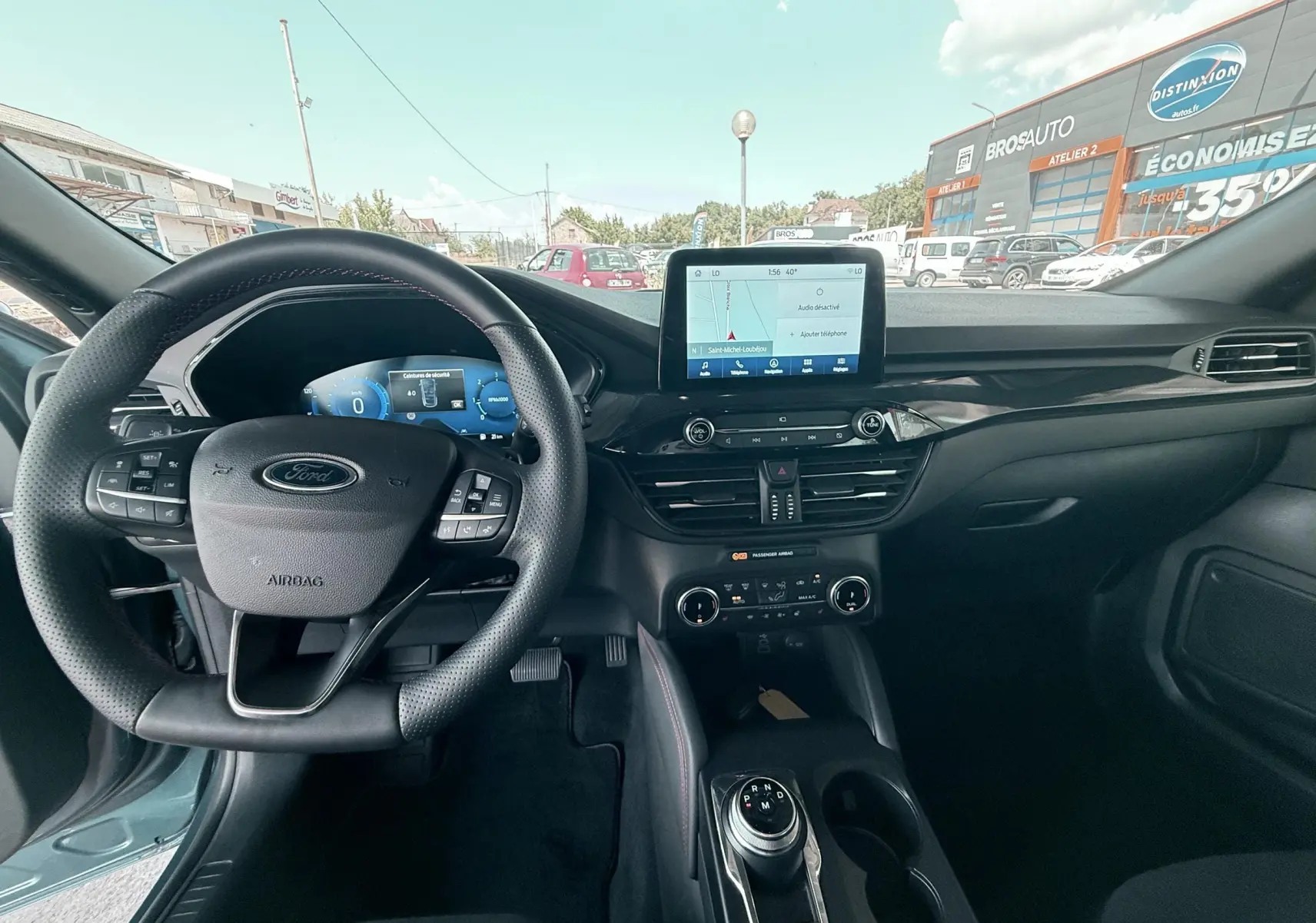 Vue intérieure avant du Ford Kuga 2023 bleu azur, tableau de bord avec écran tactile et volant multifonction noir.