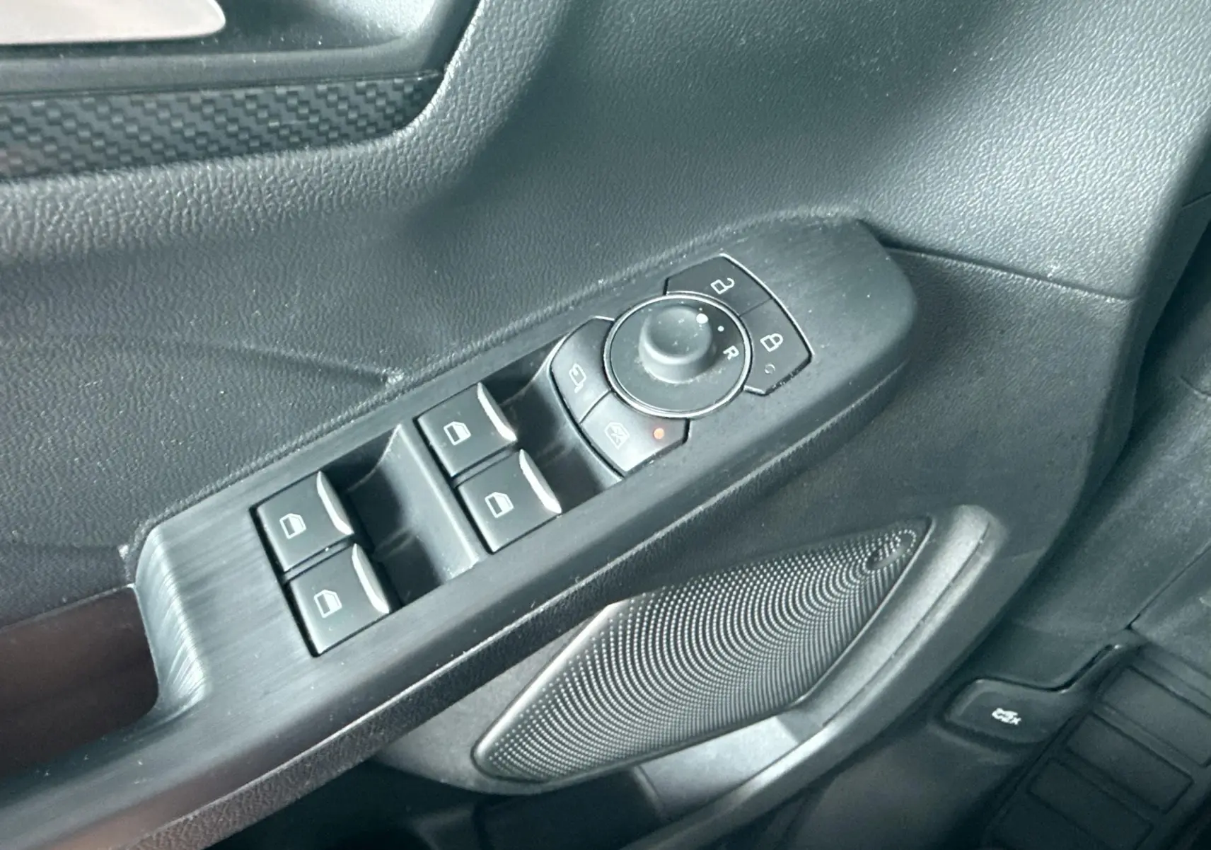 Gros plan sur la commande des vitres et rétroviseurs côté conducteur du Ford Kuga 2023, intérieur noir.