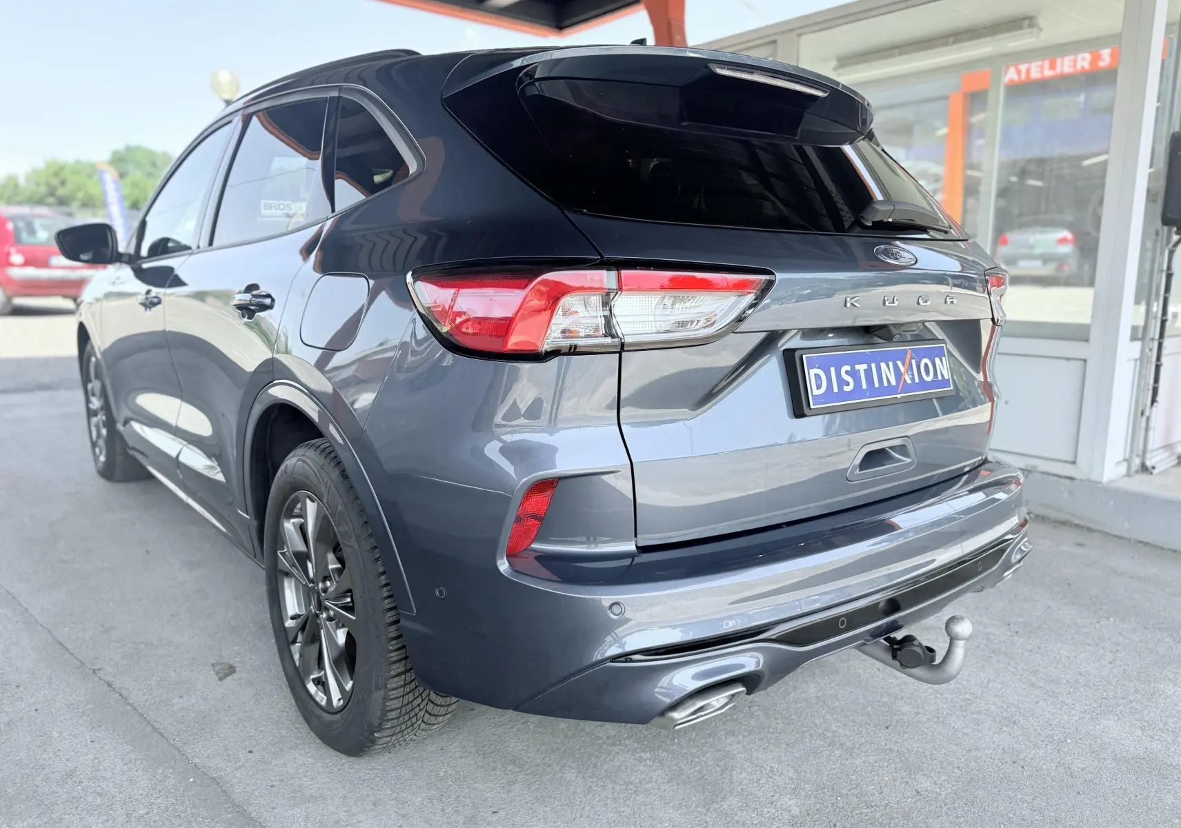 Vue 3/4 arrière droite du Ford Kuga 2023 bleu azur avec attelage rétractable et double sortie d'échappement ST-Line.
