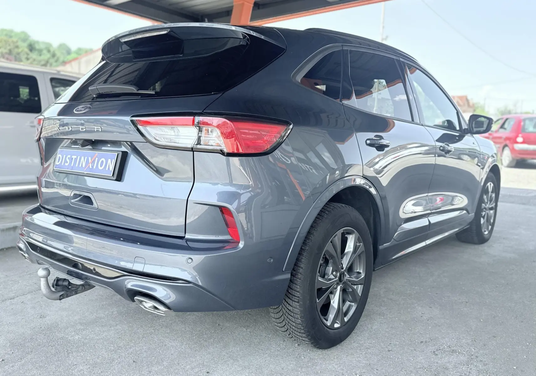 Vue 3/4 arrière droite du Ford Kuga bleu azur 2023 avec attelage rétractable et double sortie d'échappement ST-Line.