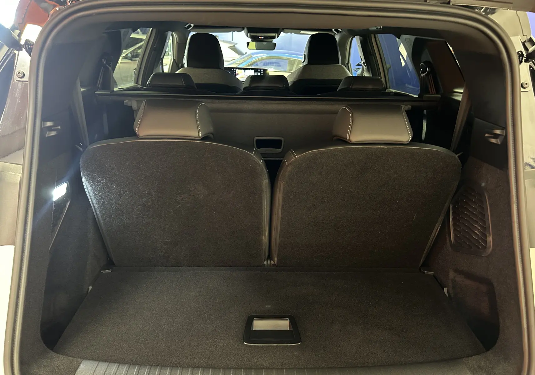 Vue arrière du coffre ouvert du Peugeot 5008 Hybrid blanc, montrant les sièges rabattus et l'intérieur spacieux.