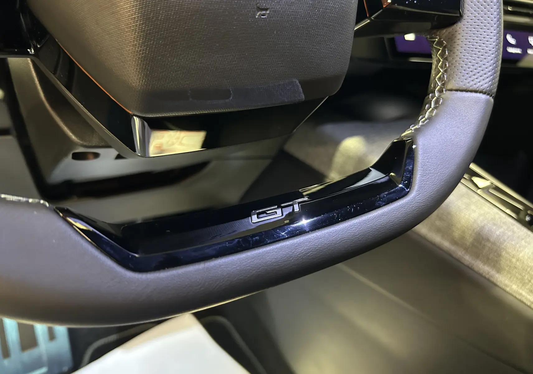 Gros plan sur le volant noir avec logo GT du Peugeot 5008 Hybrid 145ch, intérieur moderne et finition soignée.