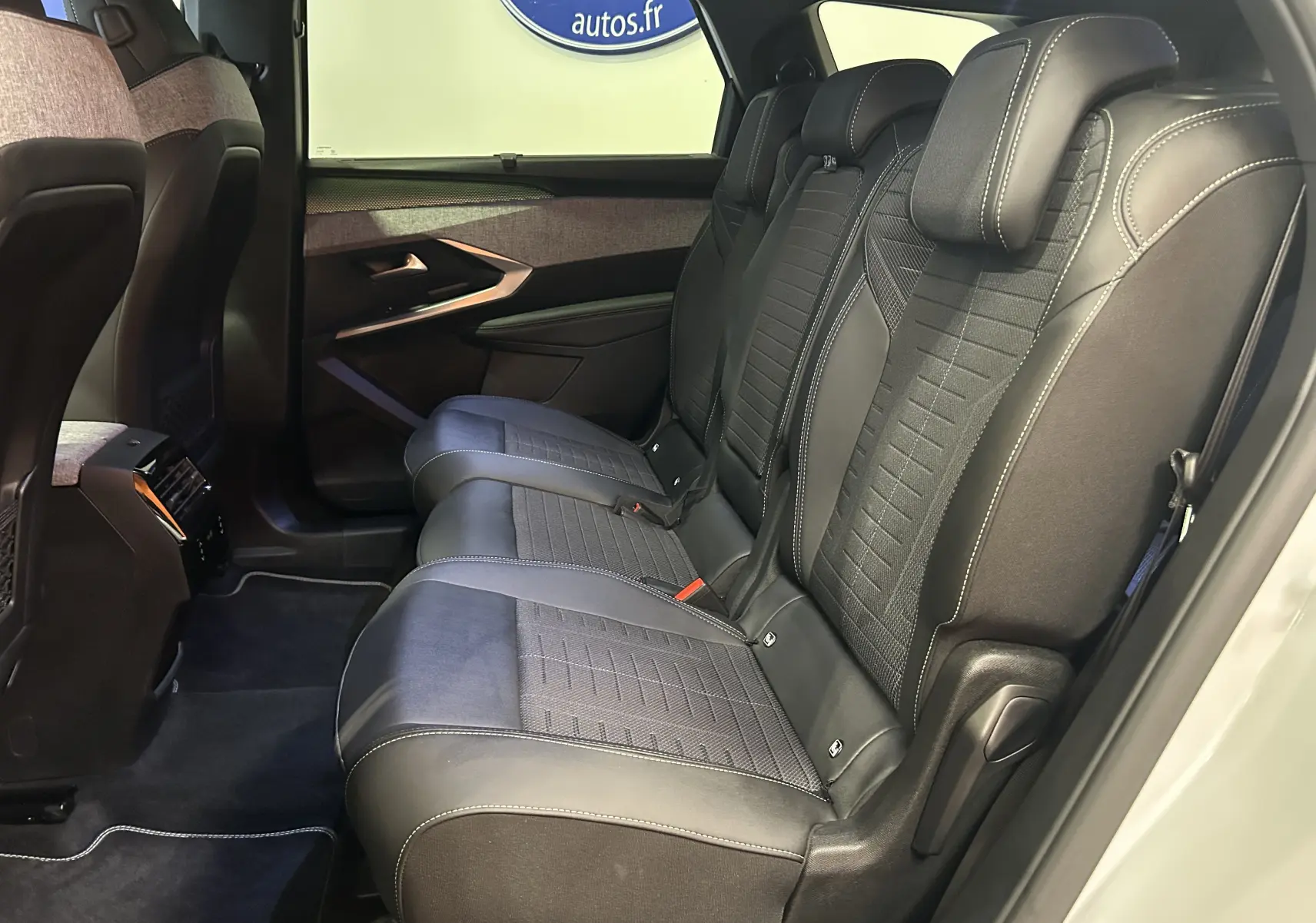 Vue intérieure côté droit des sièges arrière en cuir noir avec surpiqûres blanches du Peugeot 5008 Hybrid 2025 blanc.