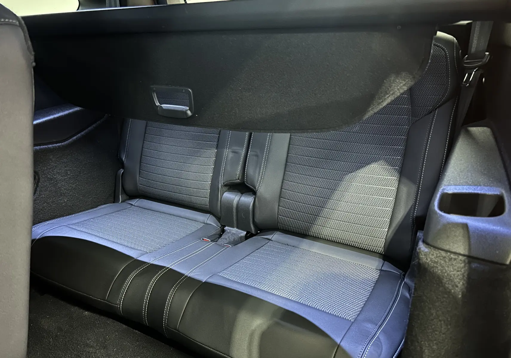 Vue rapprochée des sièges arrière en tissu et cuir noir du Peugeot 5008 Hybrid 2025, avec habillage intérieur sombre.