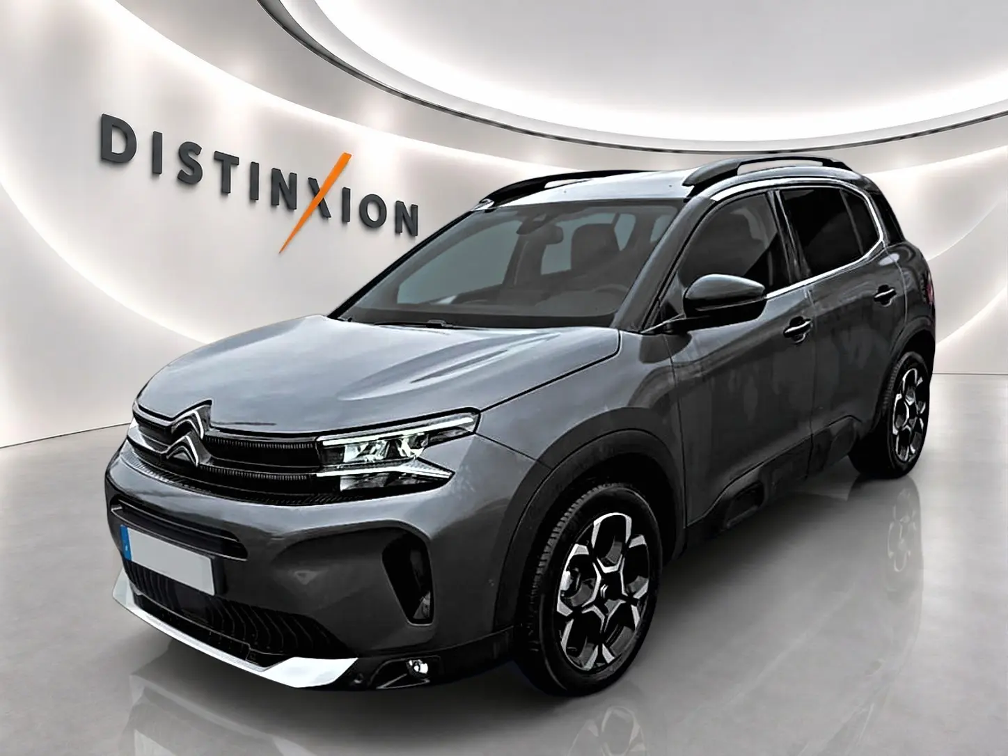 Citroën C5 Aircross gris en 3/4 avant droit, avec jantes alu et barres de toit noires visibles.