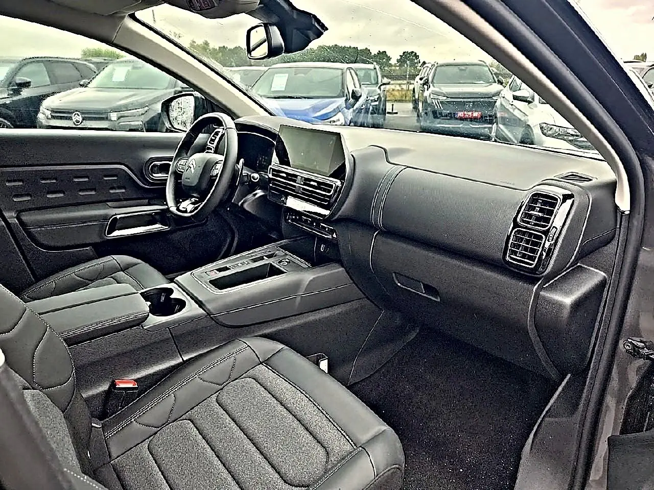 Intérieur avant du Citroën C5 Aircross gris 2025, vue côté passager avec tableau de bord moderne et écran tactile.
