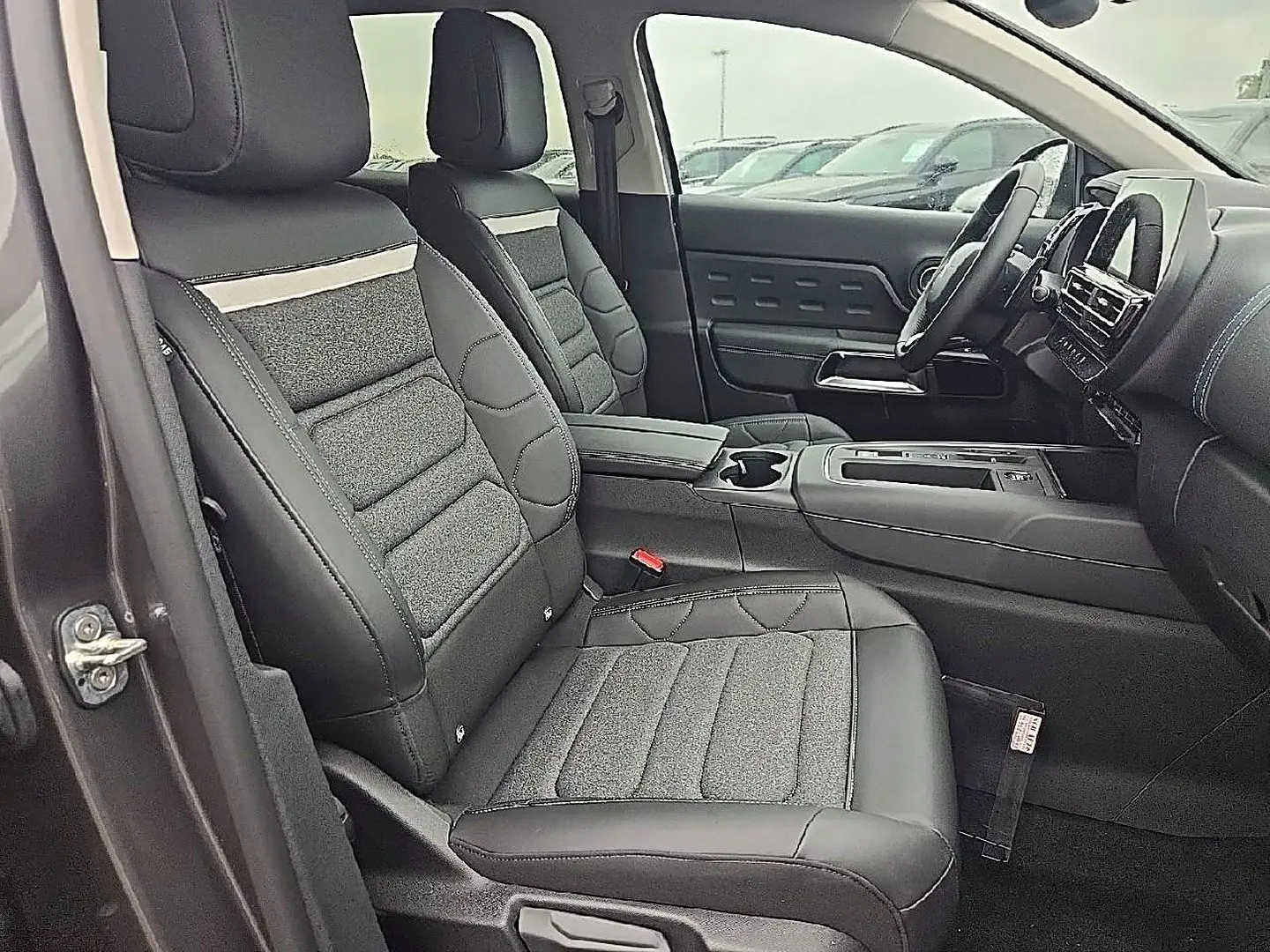 Vue intérieure côté conducteur du Citroën C5 Aircross 2025 gris, sièges tissu et cuir noirs avec tableau de bord moderne.