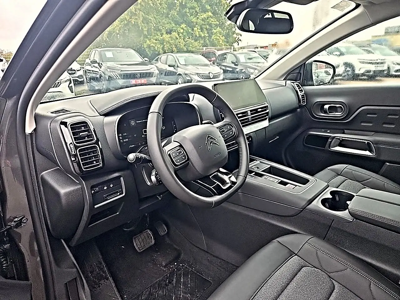 Intérieur avant du Citroën C5 Aircross gris 2025, vue côté conducteur, volant cuir multifonction et écran tactile central.