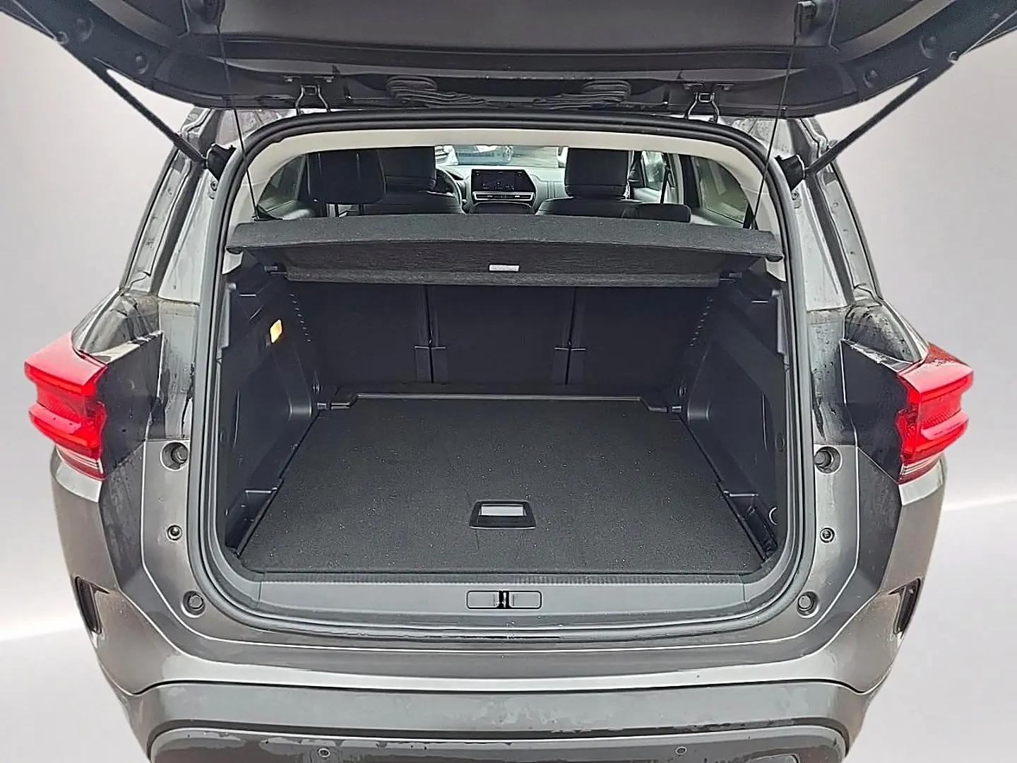 Coffre ouvert vu de l'arrière d'un Citroën C5 Aircross gris 2025, montrant l'espace de chargement et la tablette cache-bagages.