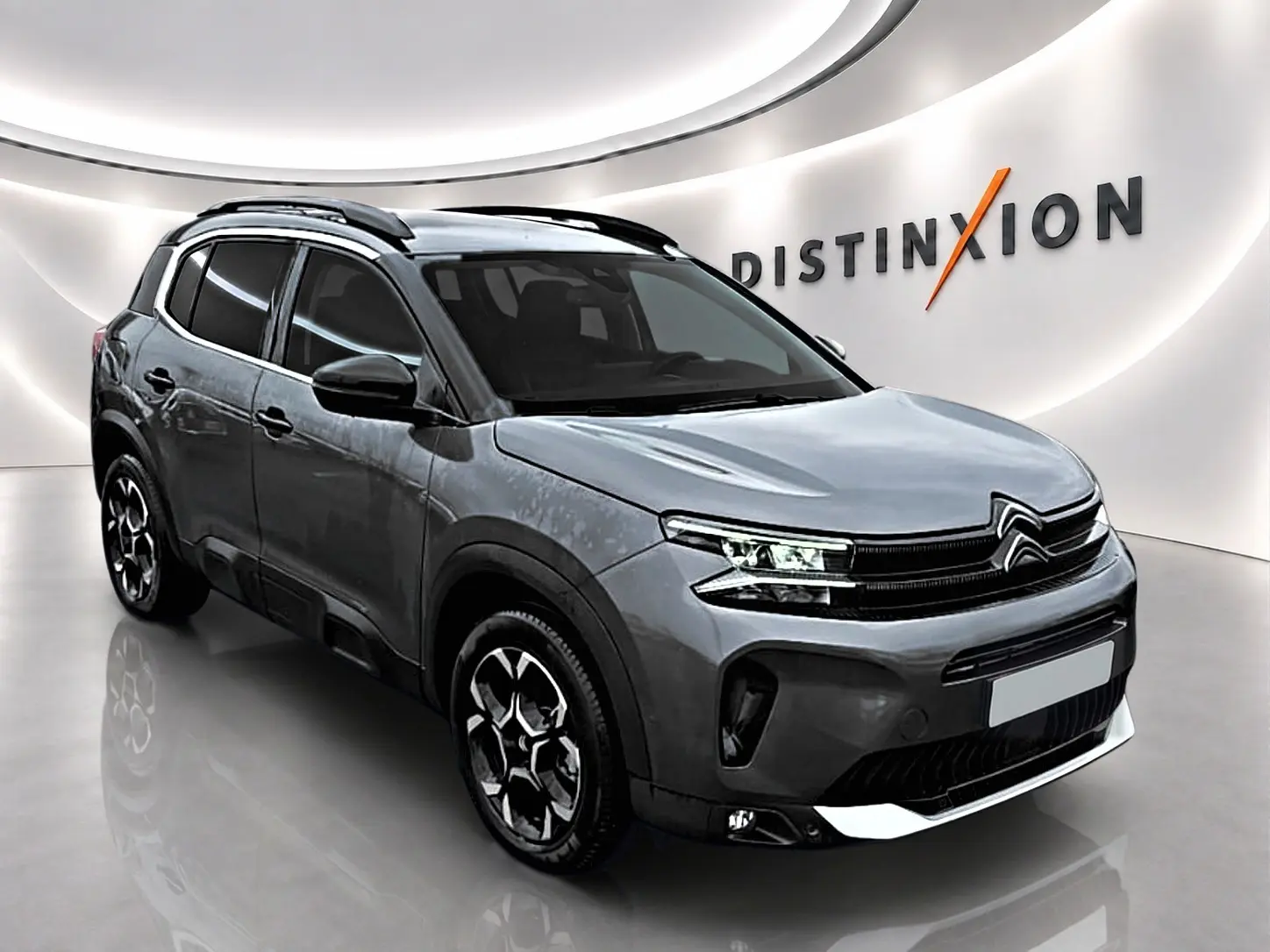 Citroën C5 Aircross gris en 3/4 avant droit, avec barres de toit et jantes alliage distinctives.