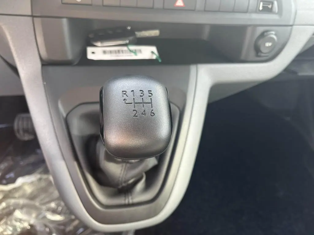 Gros plan sur le levier de vitesses manuel noir du Peugeot Expert Fourgon gris platinium, intérieur avant.