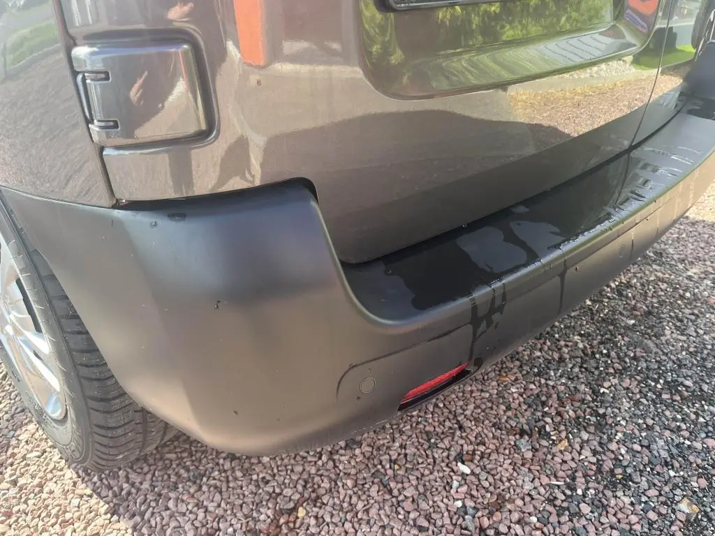 Gros plan sur le pare-chocs arrière gris platinium métallisé du Peugeot Expert Fourgon, avec capteur de stationnement visible.