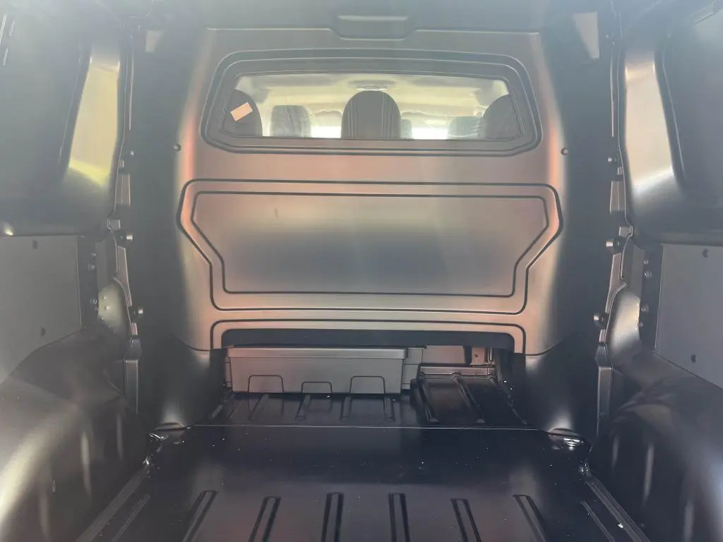 Vue intérieure arrière du Peugeot Expert Fourgon gris platinium, montrant la cloison pleine avec vitre plexiglass et espace de chargement.