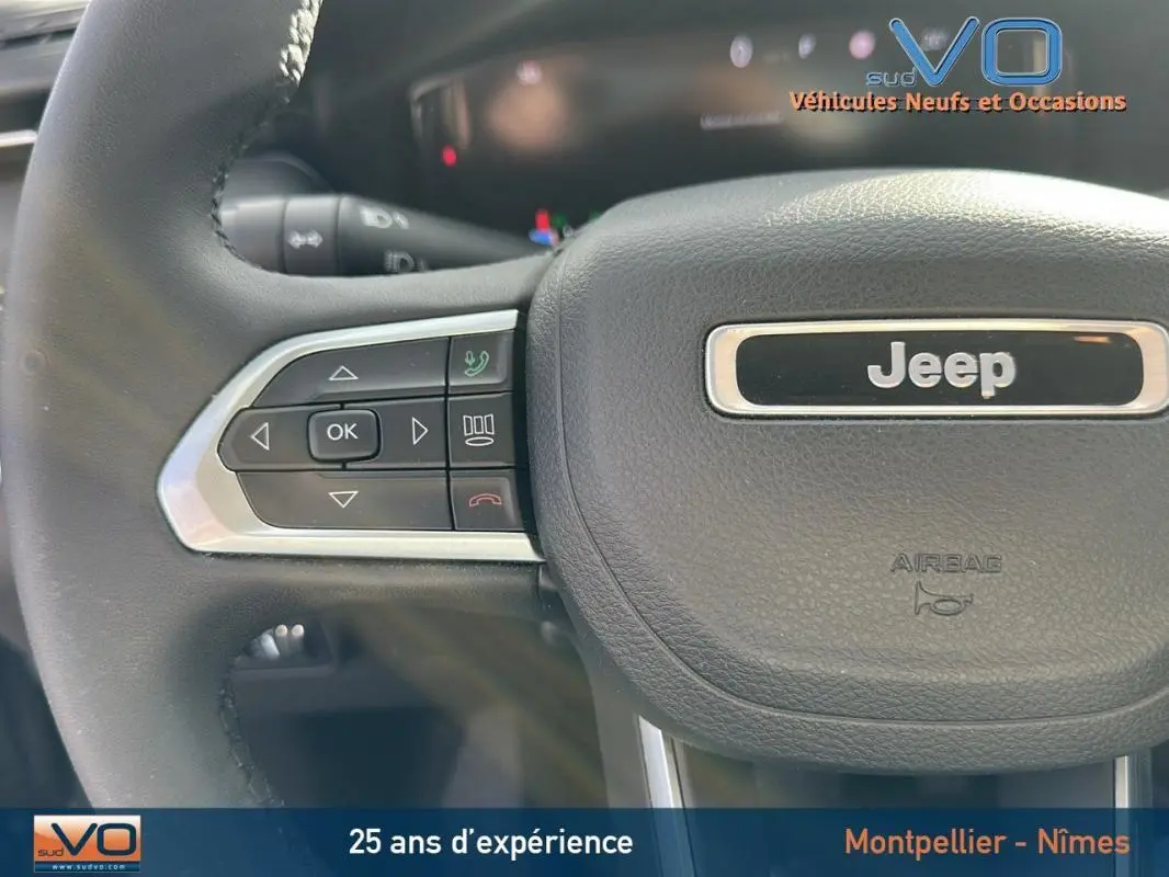 Gros plan sur le volant noir du Jeep Compass 2024 avec commandes intégrées et logo central visible.