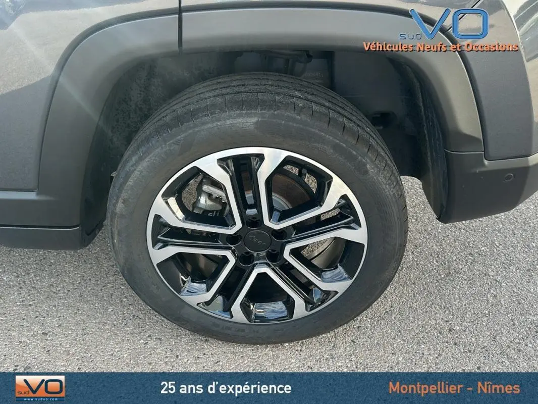 Gros plan sur la roue avant droite du Jeep Compass gris 2024 avec jante alliage bicolore et logo Jeep au centre.