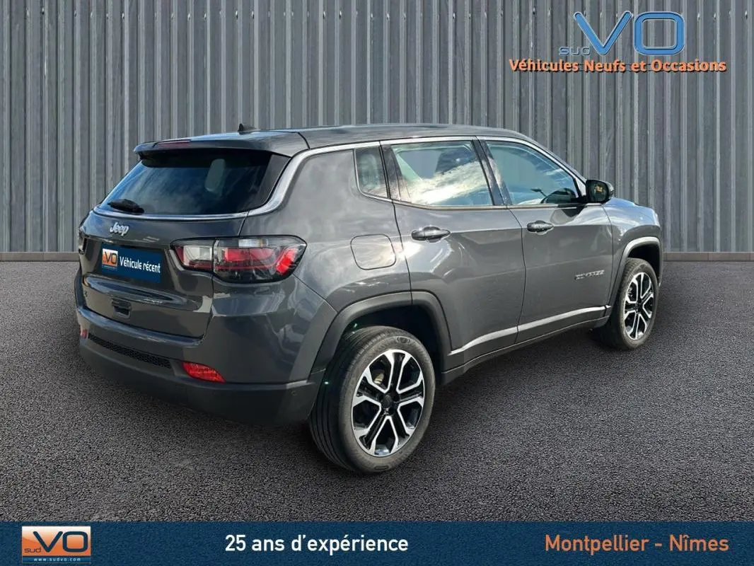 Vue 3/4 arrière droite d'un Jeep Compass gris 2024 avec jantes alliage et vitres teintées sur fond urbain.