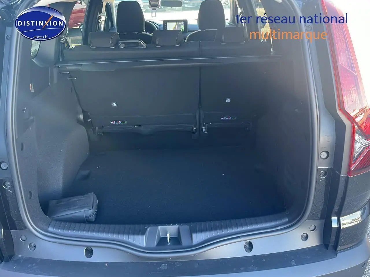 Coffre ouvert vu de l'arrière d'un Dacia Jogger noir nacré 2024 avec banquette arrière et tablette cache-bagages.
