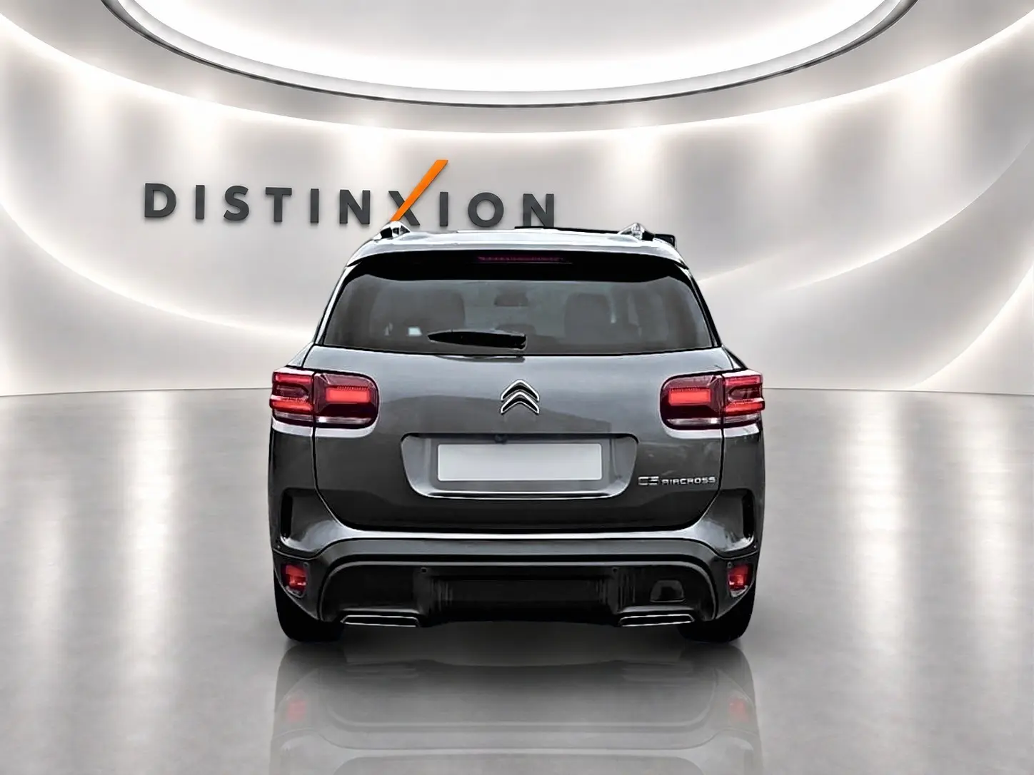 Vue arrière d'un Citroën C5 Aircross gris 2025 avec feux LED et barres de toit dans un showroom lumineux.