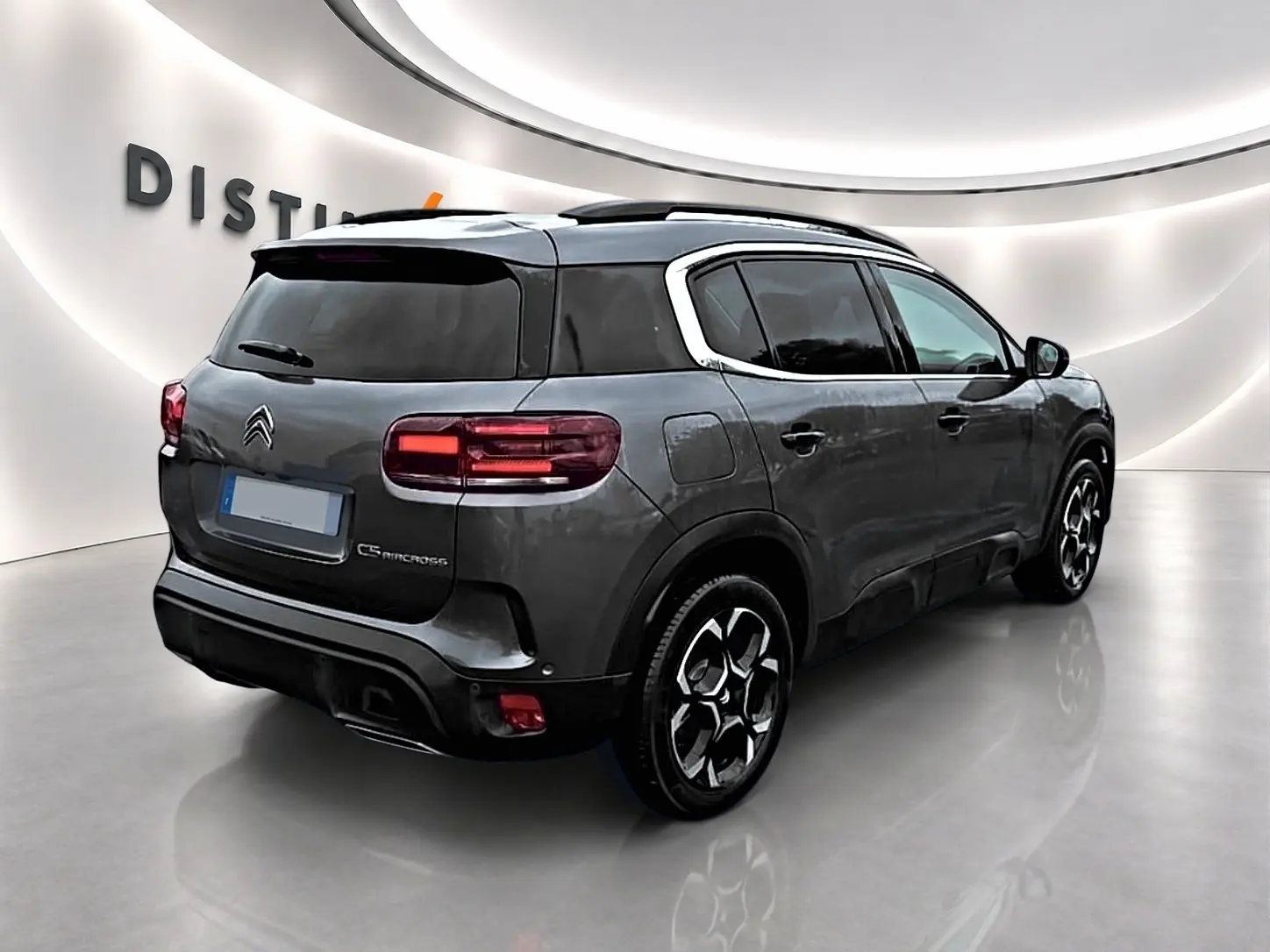 Vue 3/4 arrière droite d'un Citroën C5 Aircross gris avec vitres teintées et jantes alliage noires.