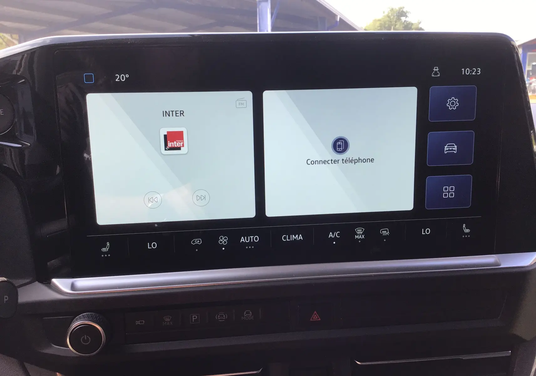 Écran tactile central du Volkswagen Transporter ProCab 2025 affichant la radio et la connexion téléphone, avec commandes climatisation intégrées.