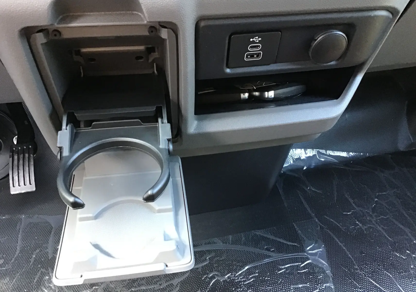 Intérieur du Volkswagen Transporter ProCab 2025, détail porte-gobelet déployé et ports USB sur console centrale grise.