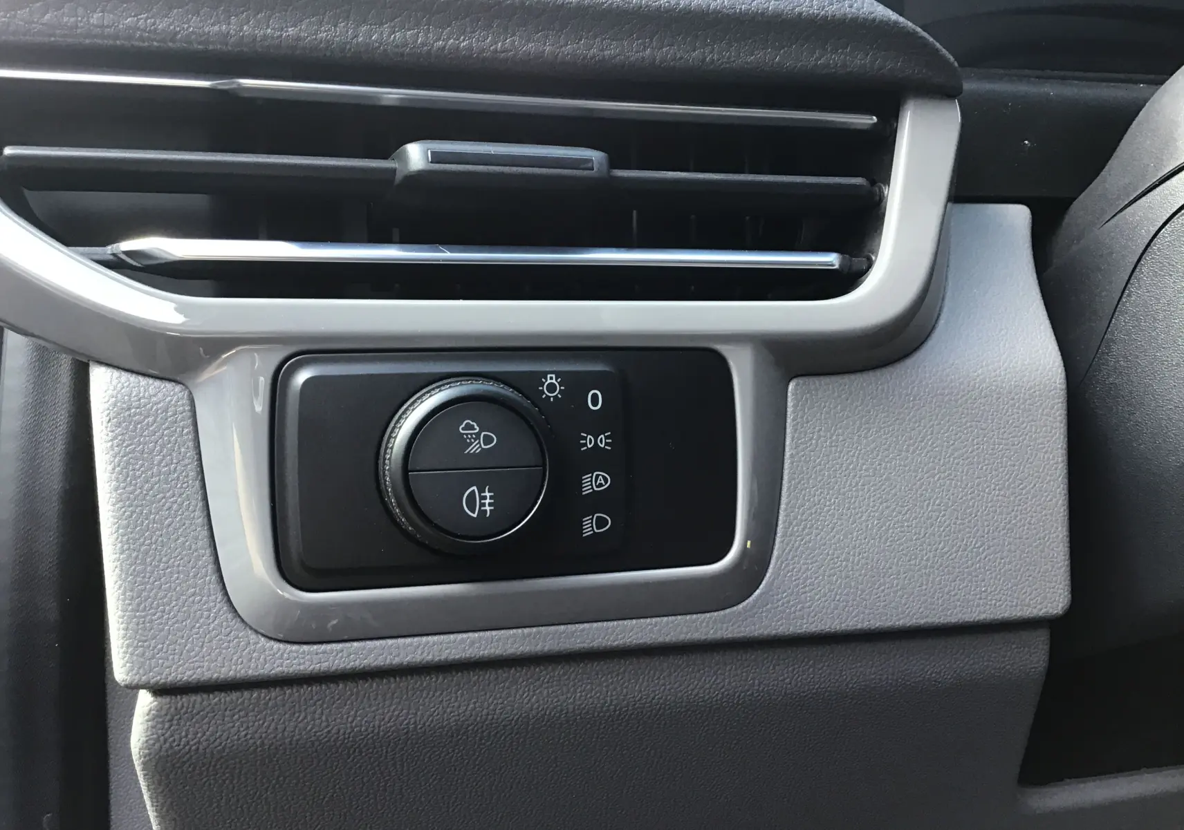 Gros plan sur la commande des phares et des feux antibrouillard du tableau de bord du Volkswagen Transporter ProCab gris anthracite.