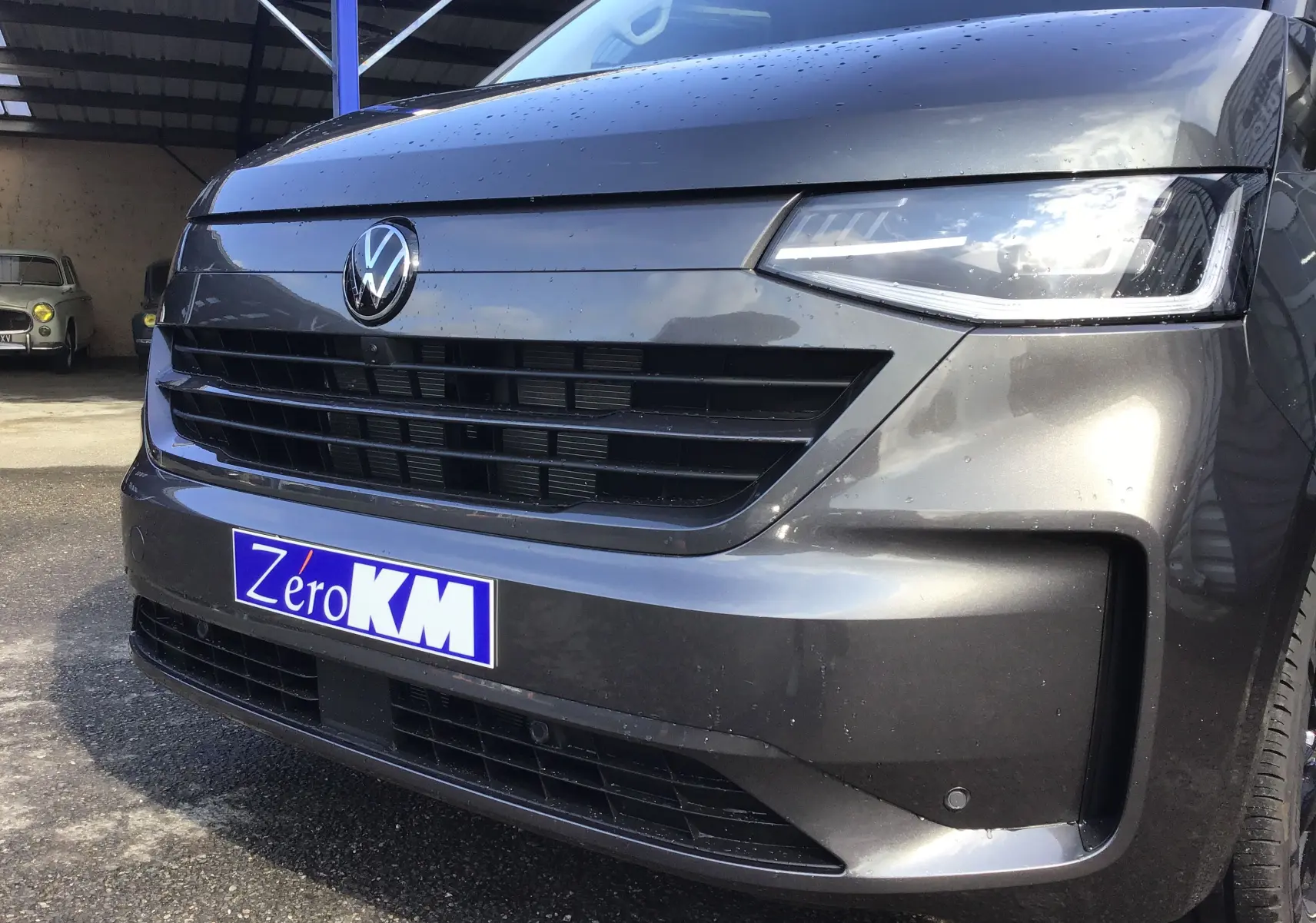 Vue rapprochée 3/4 avant droit du Volkswagen Transporter ProCab gris anthracite avec calandre et phares LED Matrix allumés.