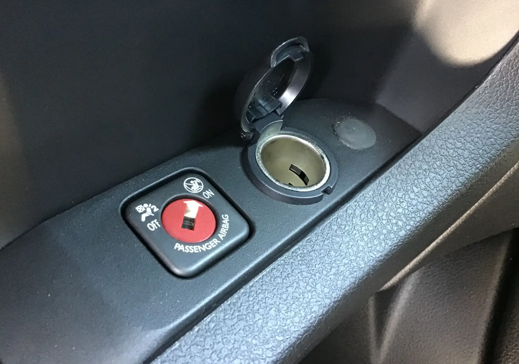 Gros plan sur le bouton de désactivation airbag passager et prise allume-cigare dans l'habitacle du Peugeot Expert Fourgon blanc.