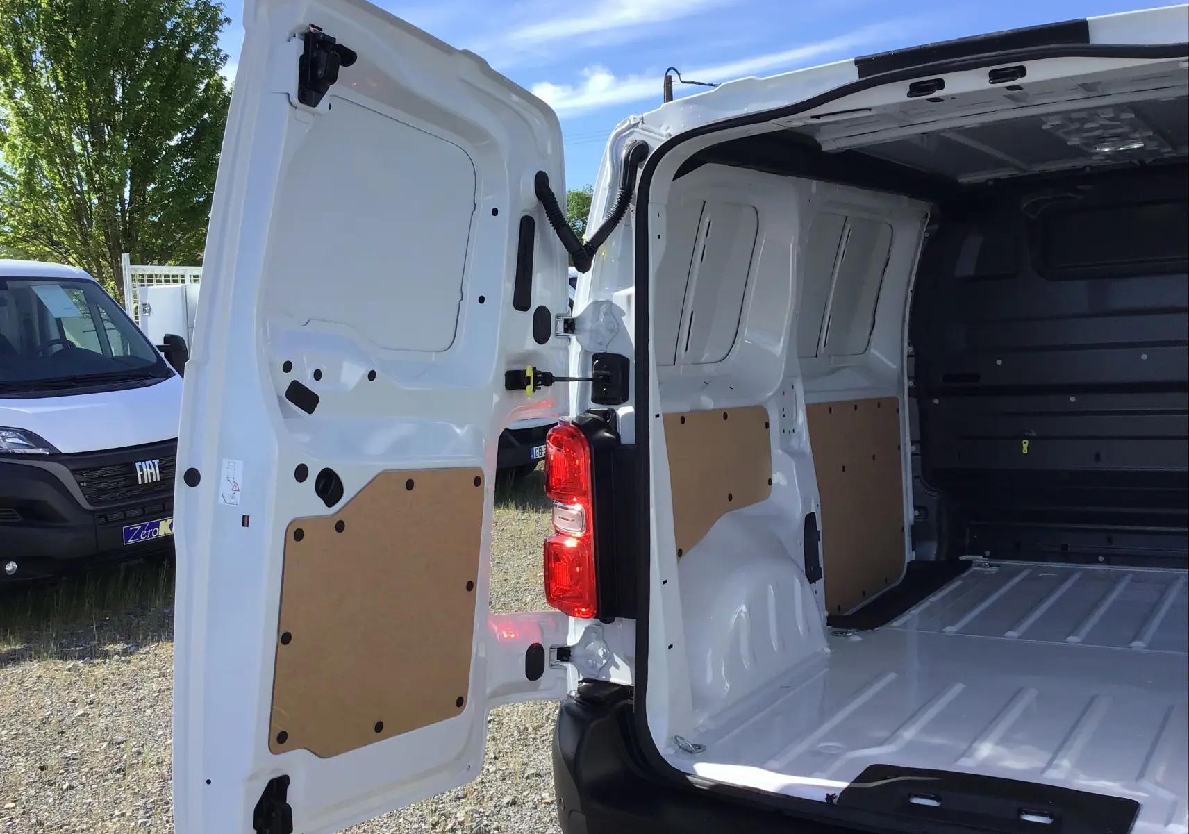 Vue arrière ouverte du Peugeot Expert Fourgon blanc 2025 montrant l'intérieur spacieux et les portes arrière battantes.