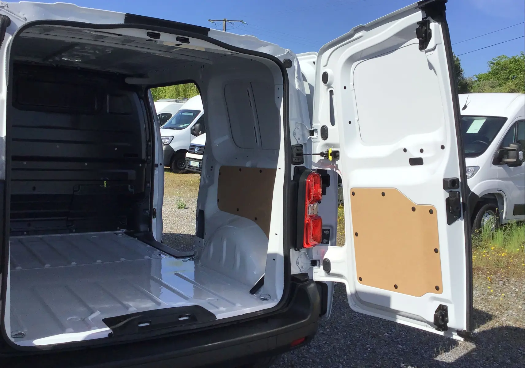 Vue arrière ouverte du Peugeot Expert Fourgon blanc 2025 montrant l’espace de chargement vide et les portes arrière battantes.
