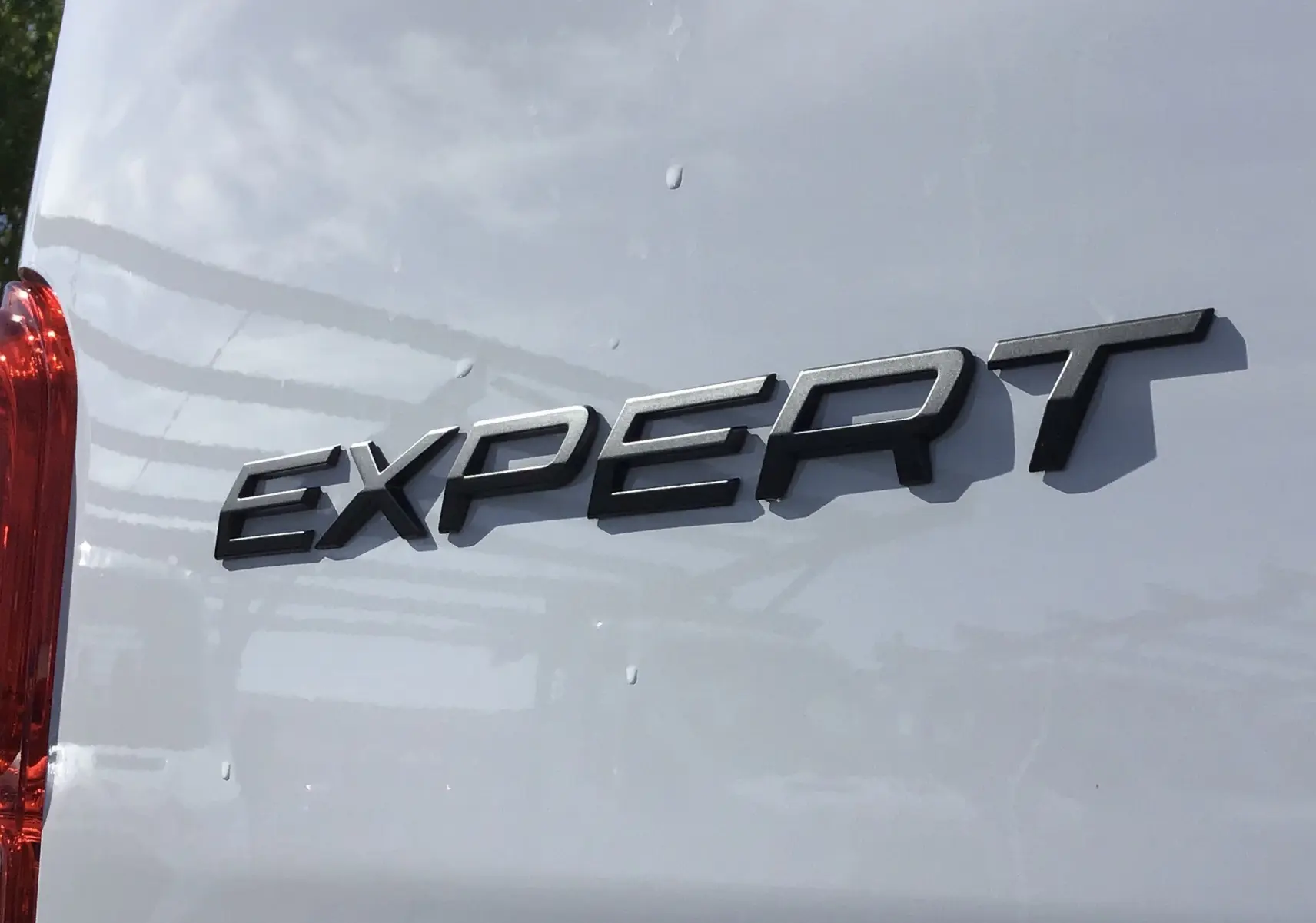 Gros plan sur l'arrière blanc du Peugeot Expert Fourgon avec l'inscription "EXPERT" en relief noir.
