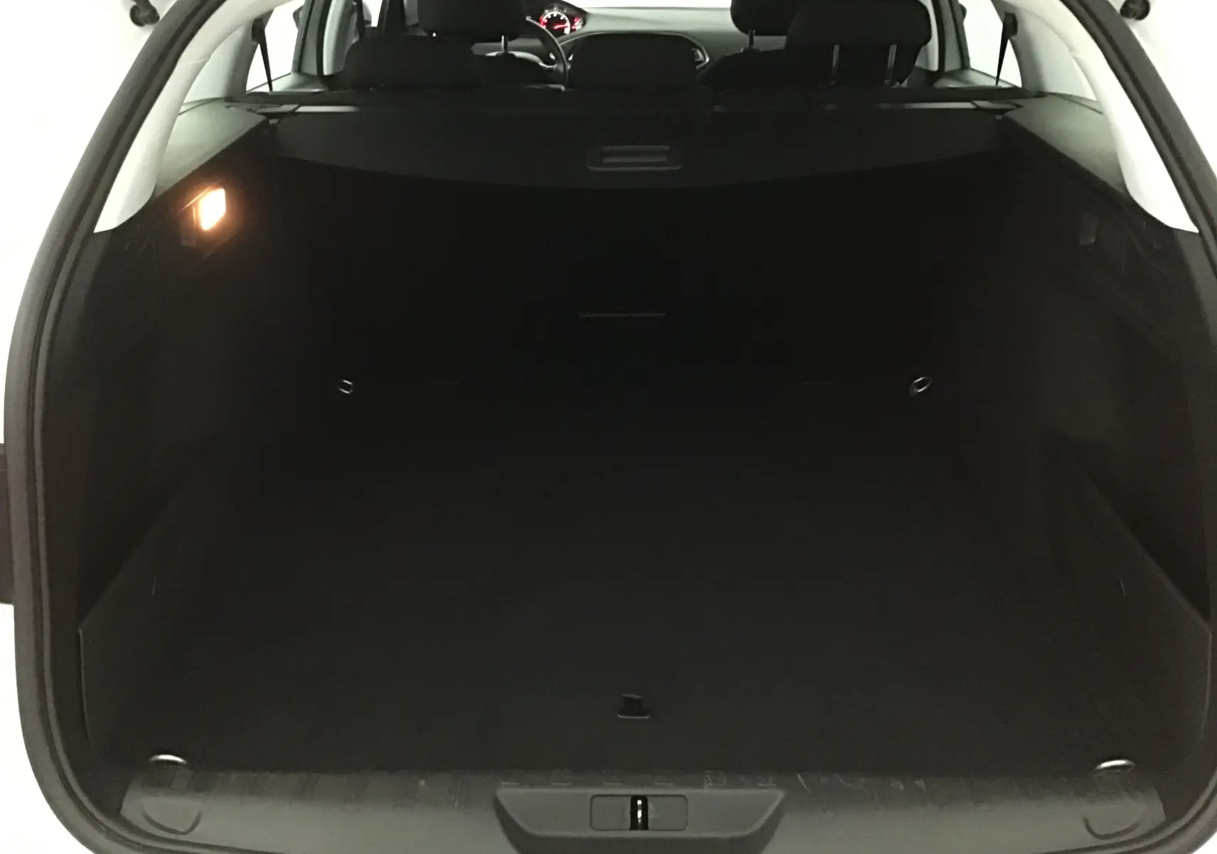 Coffre ouvert d'une Peugeot 308 SW blanche, vue arrière montrant l'espace de chargement vide et l'intérieur sombre.