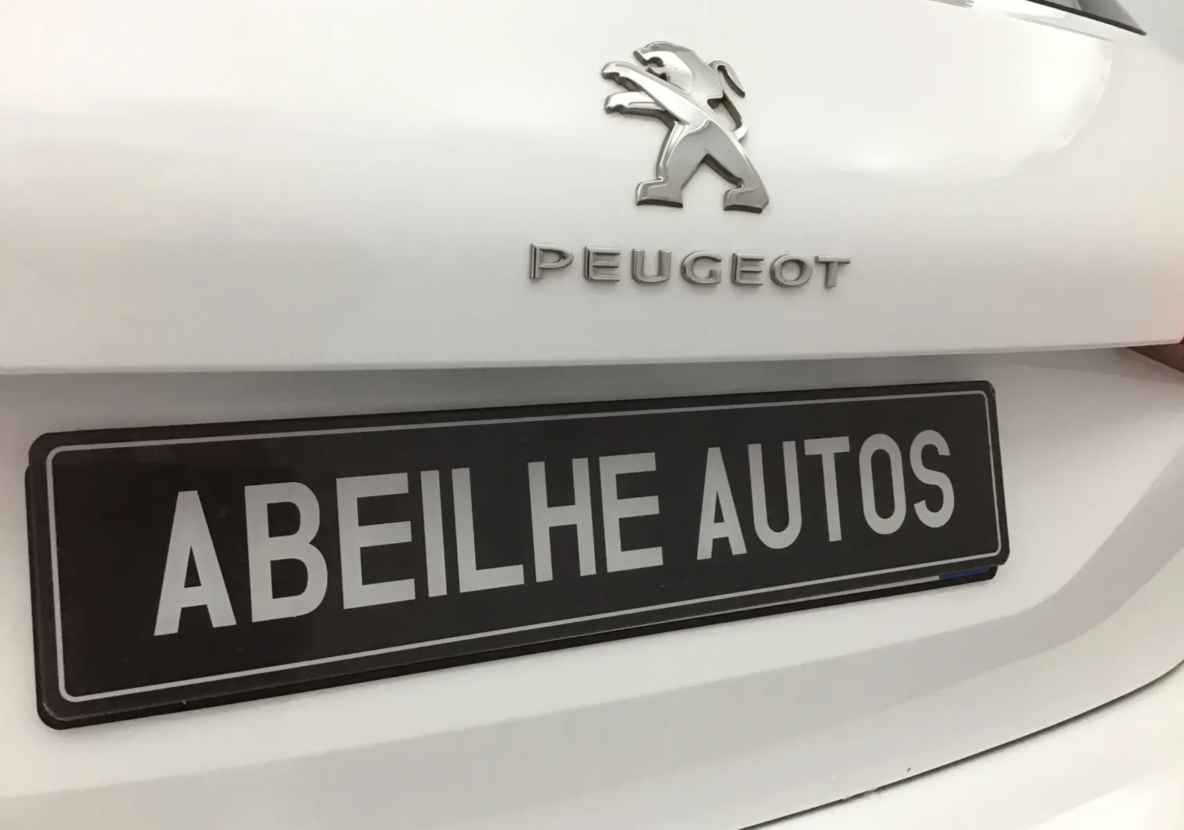 Gros plan sur l'arrière blanc d'une Peugeot 308 SW avec logo et plaque d'immatriculation Abeilhe Autos.