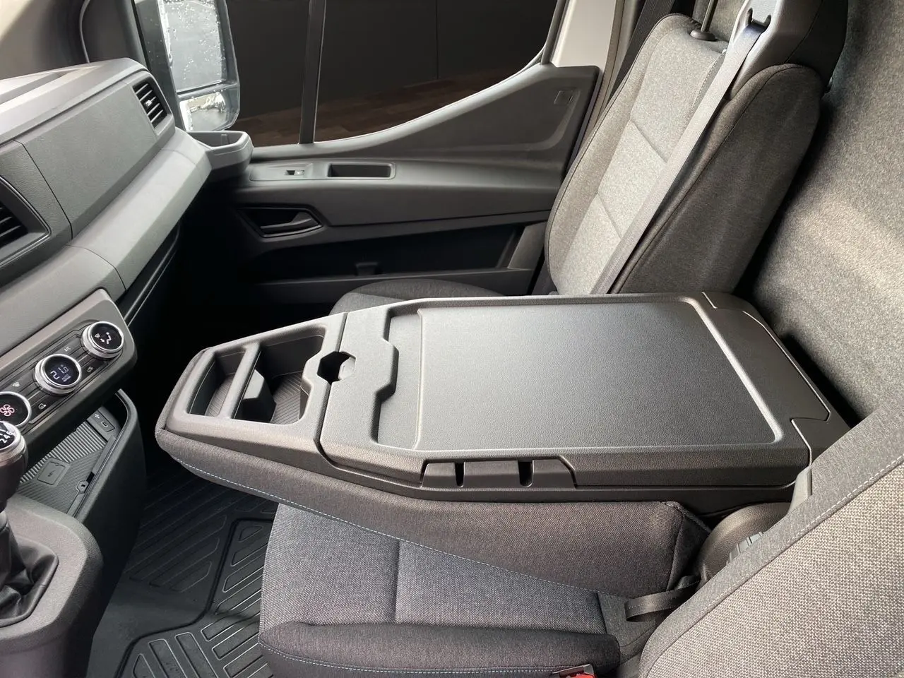 Vue intérieure côté passager du Renault Master blanc 2025, mettant en valeur la banquette avec bureau mobile intégré.